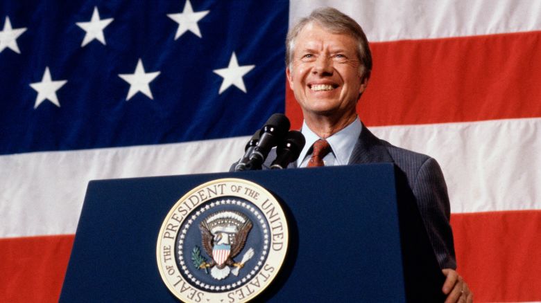 (Original Caption) 3/24/1979-Elk City, Oklahoma: President Jimmy Carter addressing a town meeting. American flag is hung in background.